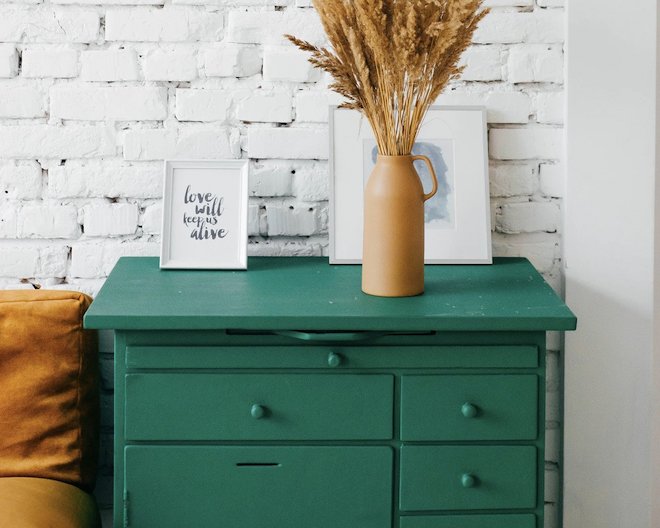 green cabinet with hobo plants and photo frame as a top decor